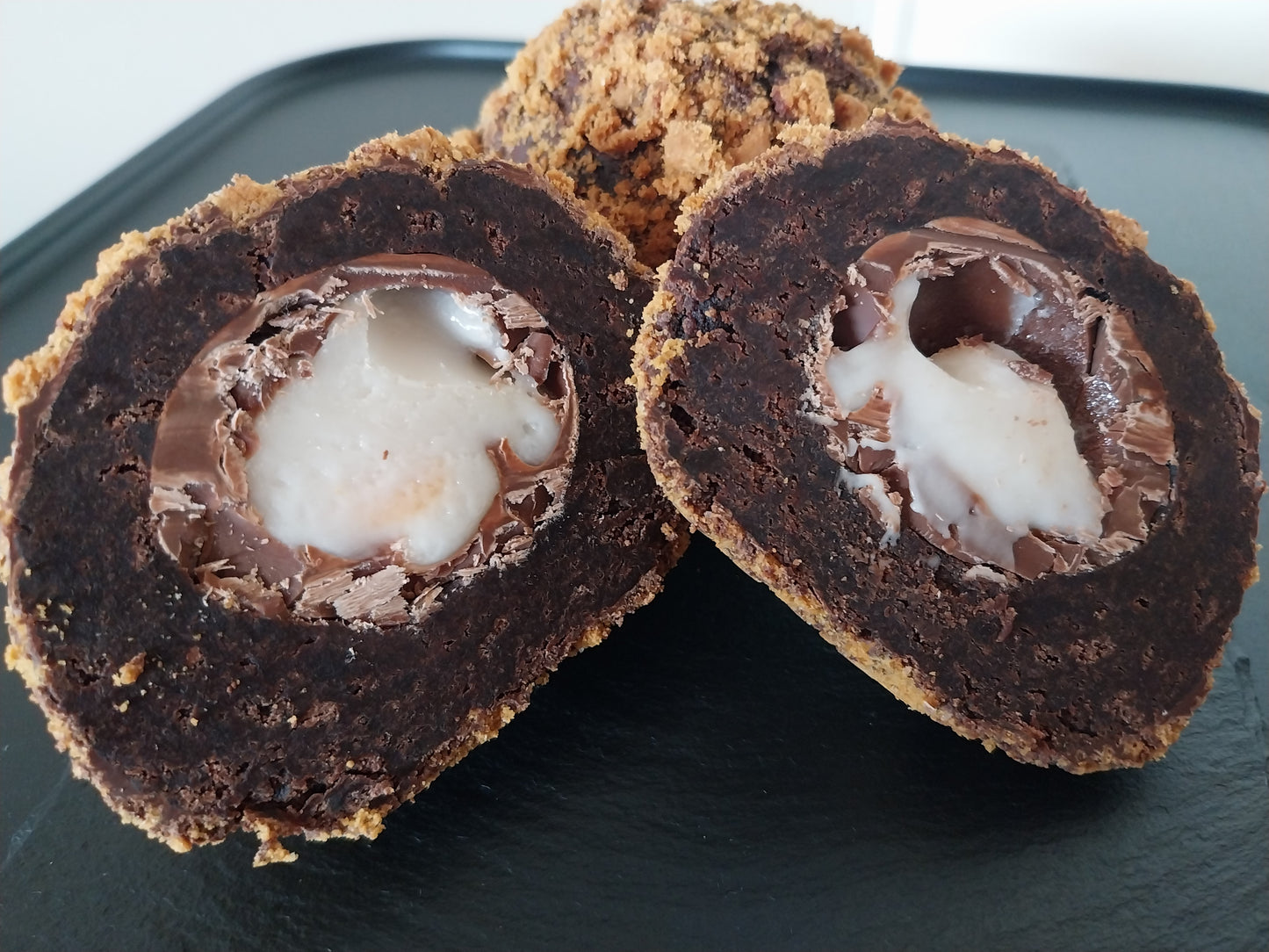 A brownie scotch egg cut open to reveal the Creme Egg centre wrapped in chocolate brownie