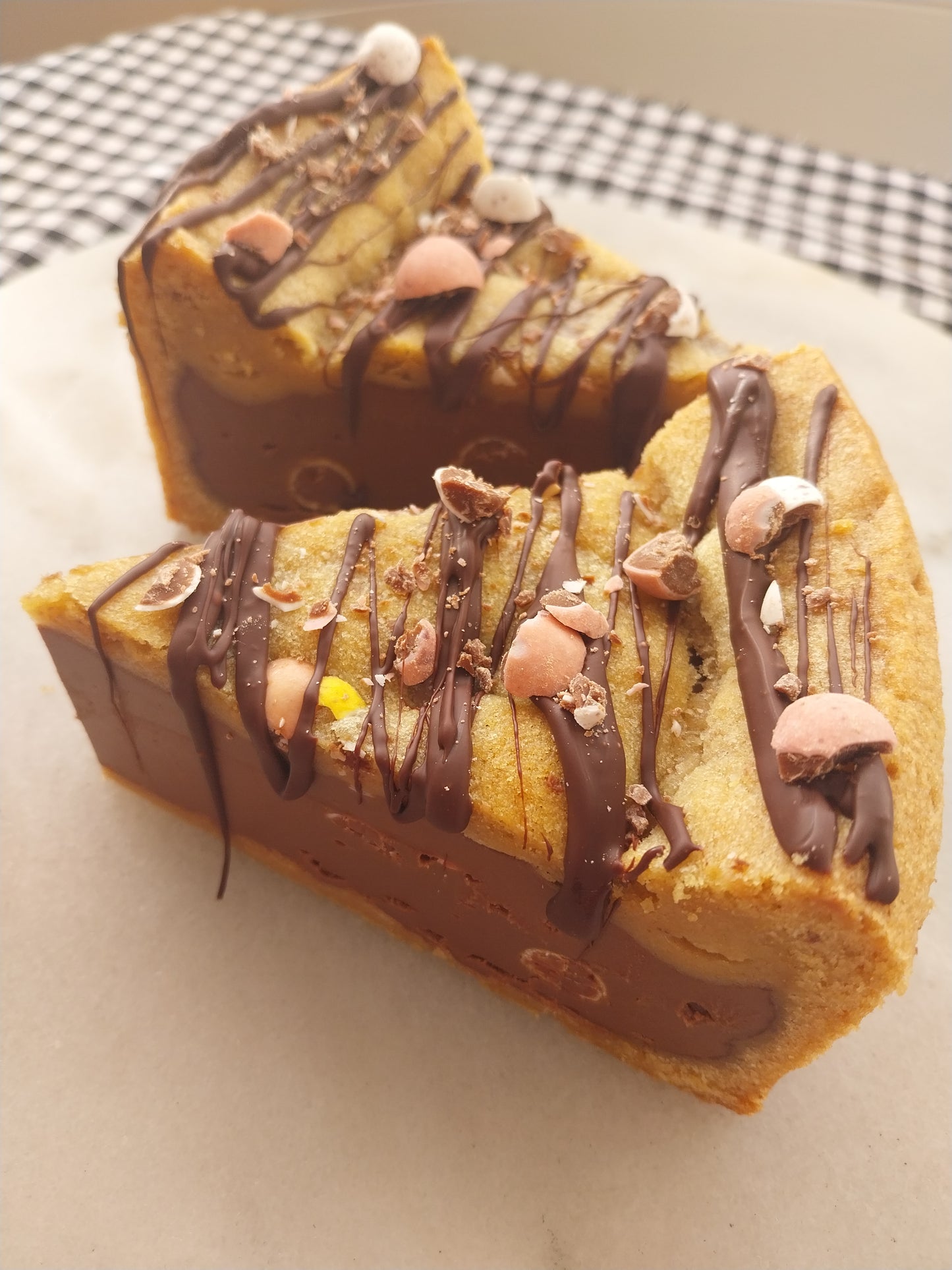 Two slices of mini egg cookie pie drizzled with dark chocolate and decorated with Mini Eggs