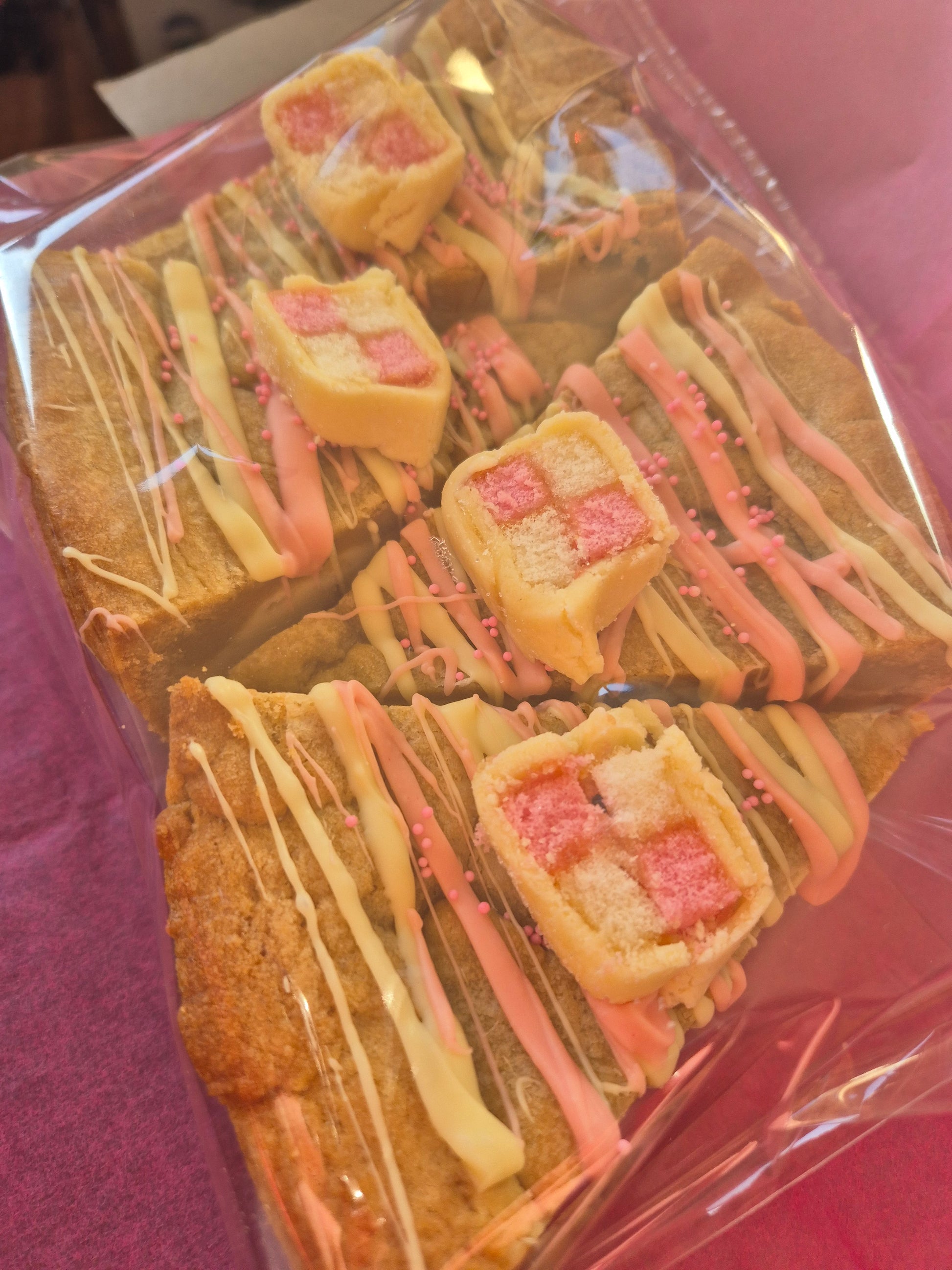 4 slices of battenberg cookie pie slices wrapped in clear cellophane on pink tissue paper