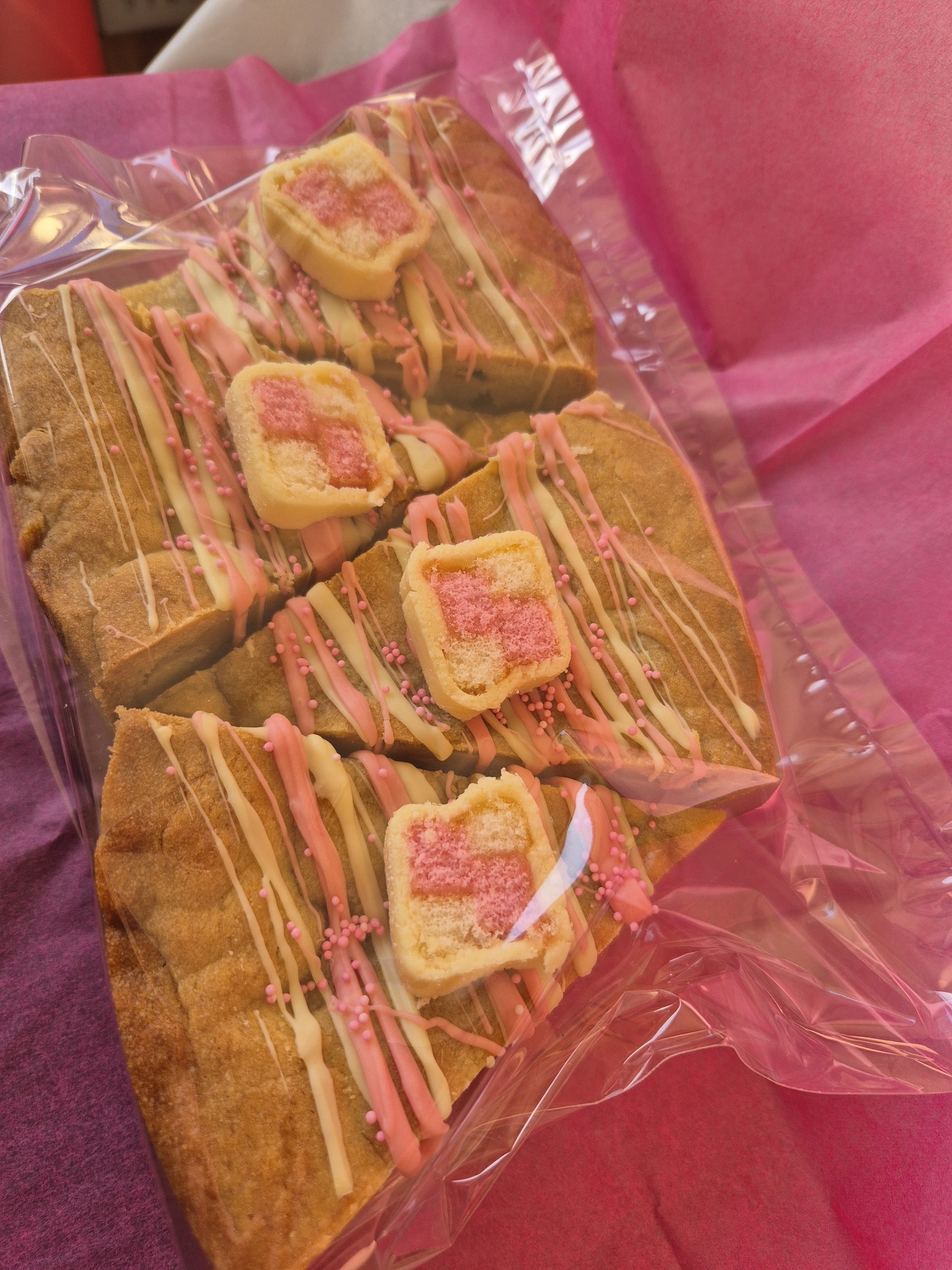 4 slices of battenberg cookie pie slices wrapped in clear cellophane on pink tissue paper