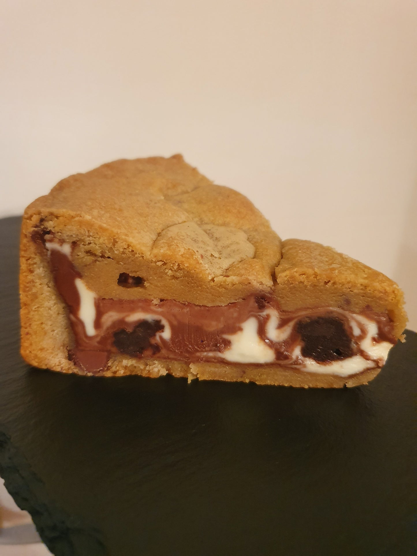 Slice of cookie pie filled with chocolate filling and chunks of brownie on a slate