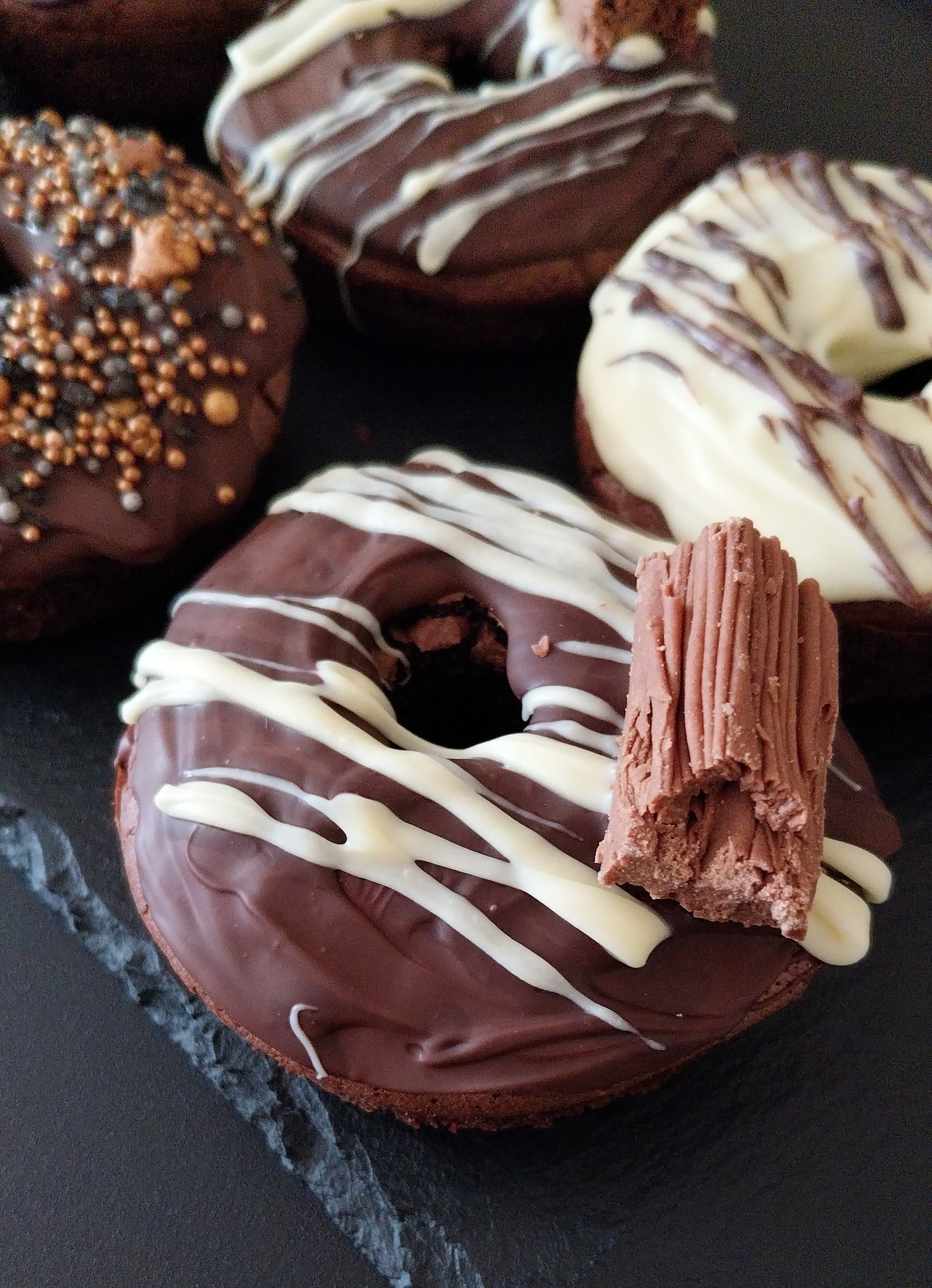 Close up of a bronut which is decorated with dark chocolate, white chocolate drizzle and a Cadbury Flake.
