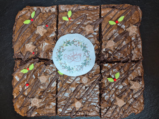 Six chocolate brownies decorated with holly sprinkles, Magic Stars and an edible wafer which says Merry Christmas