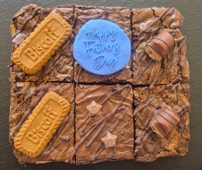 Six chocolate brownies topped with Biscoff biscuits and kinder bueno chocolate bar pieces. Includes a blue fondant topper which says Happy Father's Day