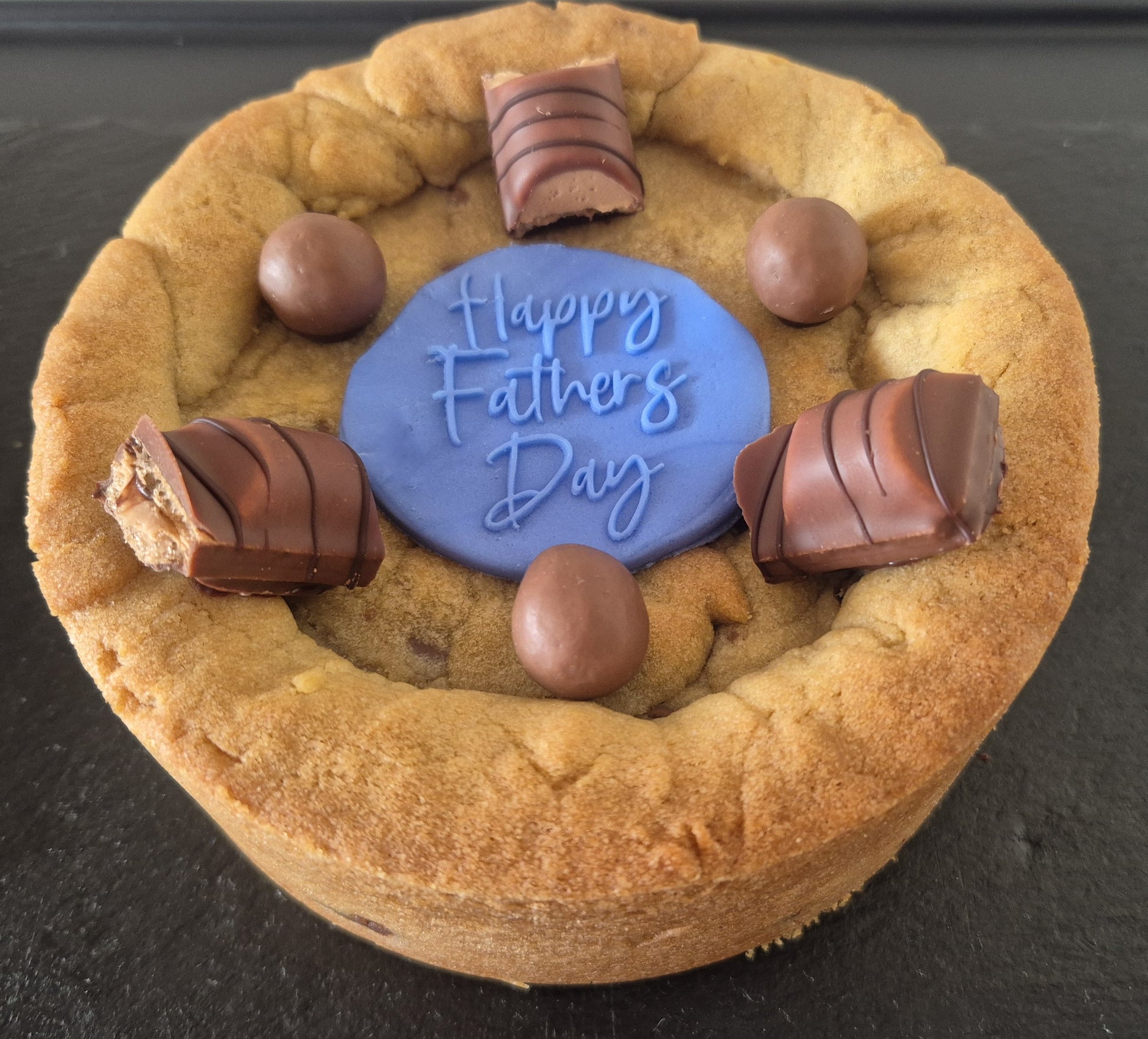 Cookie pie decorated with Kinder Bueno chocolate pieces, Maltesers and a blue fondant topper which says Happy Father's Day