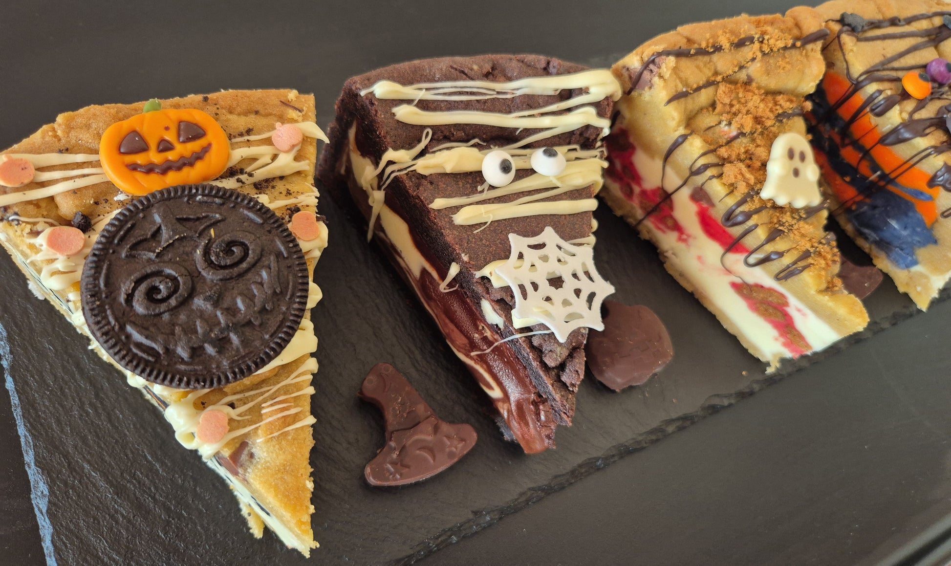 Four Halloween-themed cookie pie slices on a dark surface
