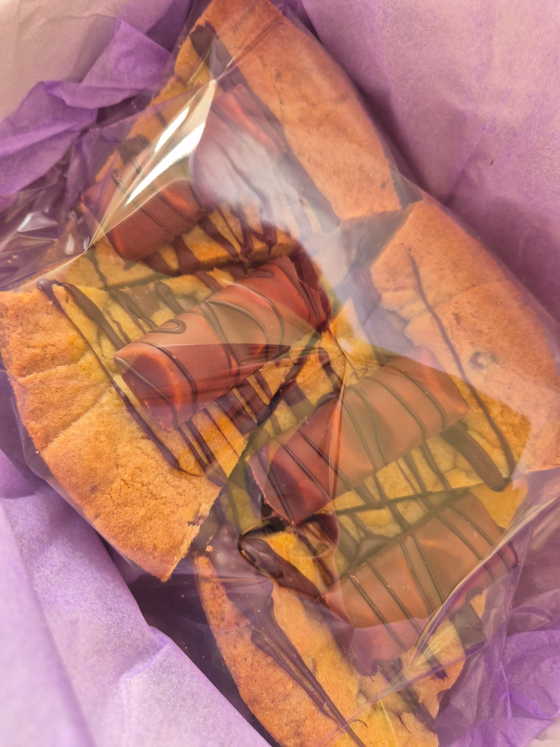 4 slices of kinder bueno cookie pie in cellophane packaging on purple tissue paper
