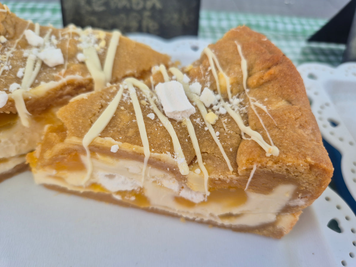 close up of a lemon meringue cookie pie slice which has been drizzled with white chocolate and topped with meringue pieces
