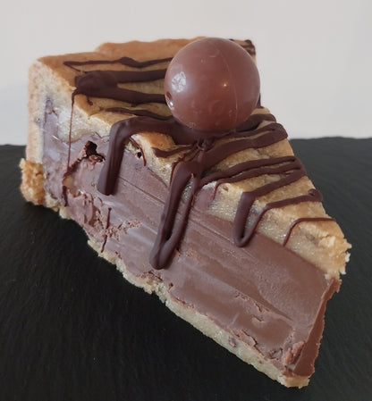 A close of a cookie pie which has a milk chocolate centre with Lindor pieces, and decorated with chocolate drizzle and a Lindor