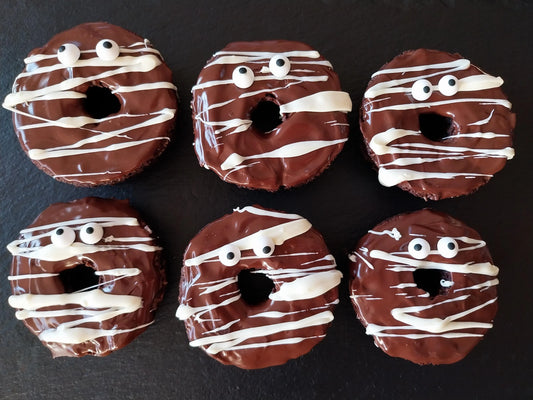 Six chocolate bronuts decorated with dark chocolate, white chocolate drizzle and candy eyes