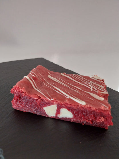 A close up of a red velvet brownie showing gooey texture and white chocolate chips